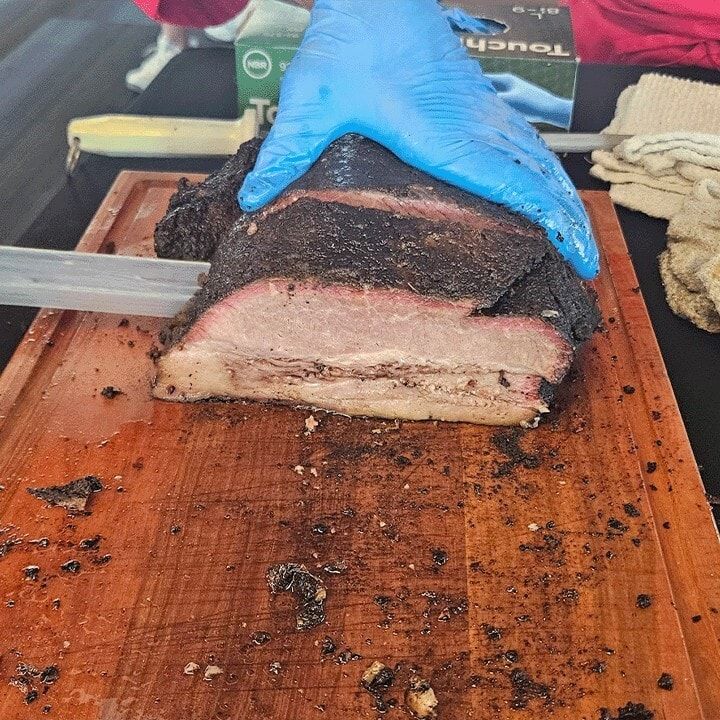 A thick slice of brisket being cut on a wooden board