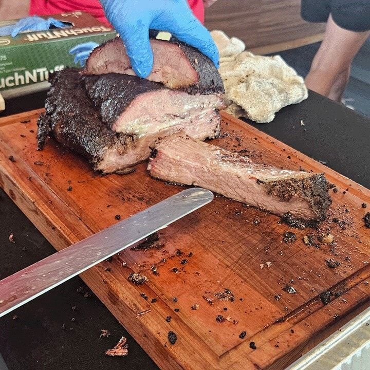 Sliced brisket with a dark bark and pink smoke ring on a wooden board