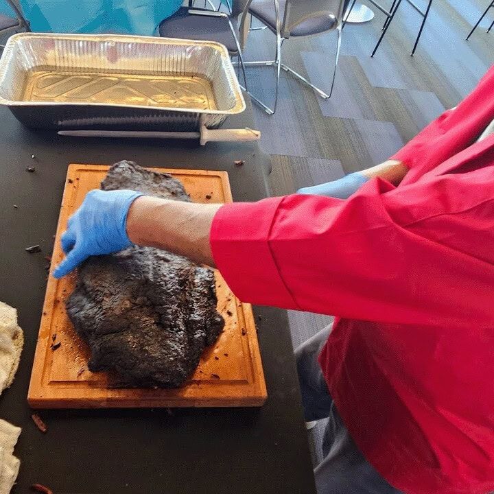 A whole pit smoked brisket resting on a wooden board